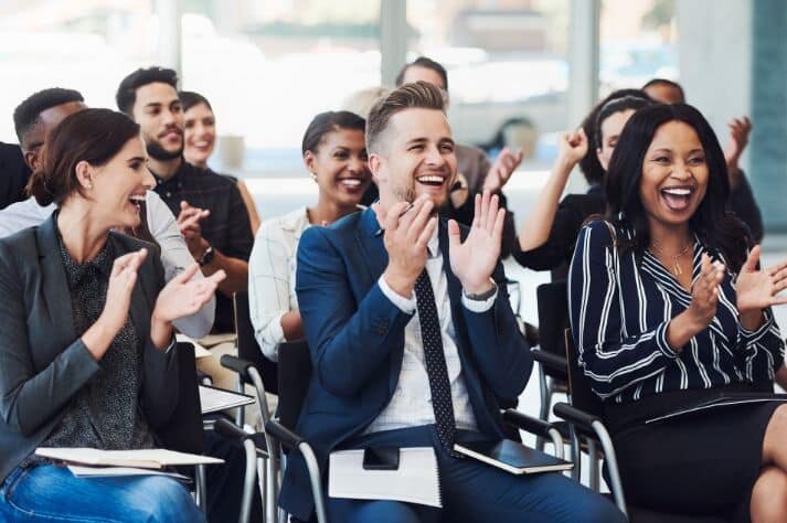 A diverse professional audience applauding a speaker